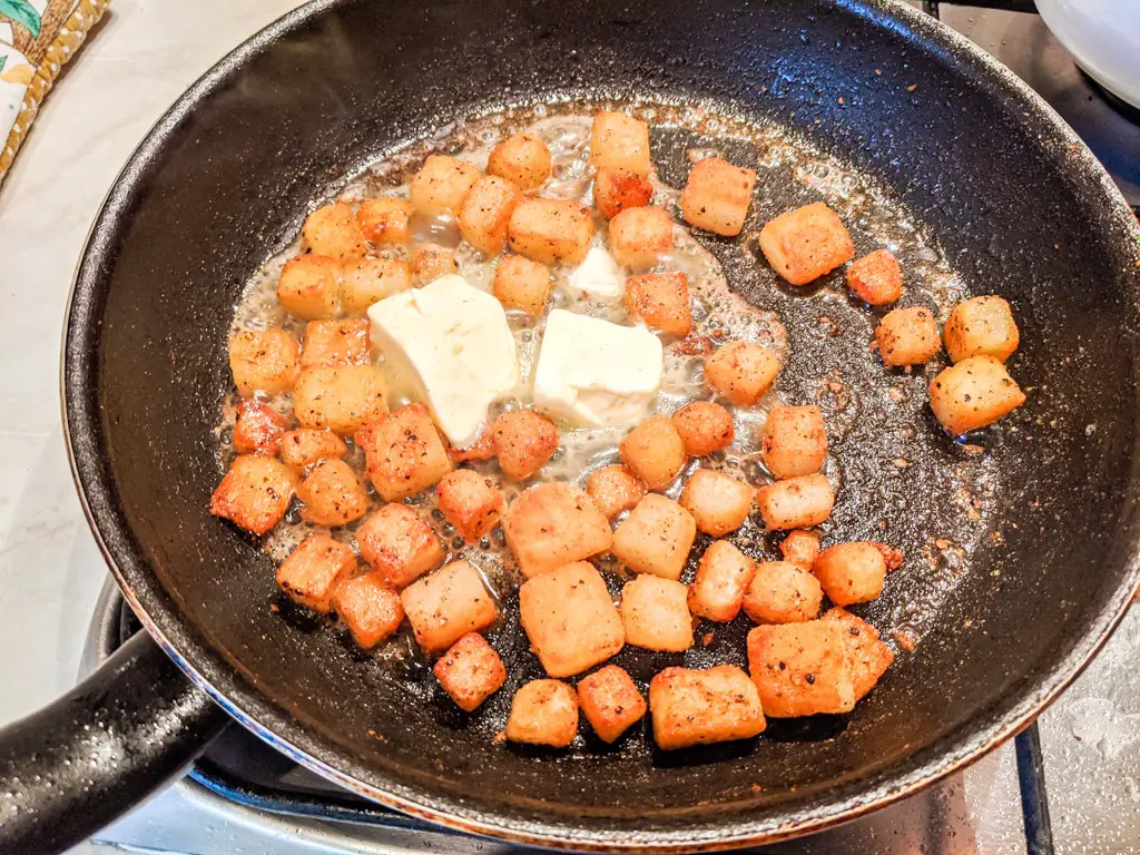 Adding butter to the browned diced potatoes