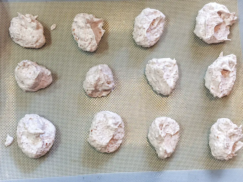 strawberry walnut meringue cookies on silicone mat and baking tray