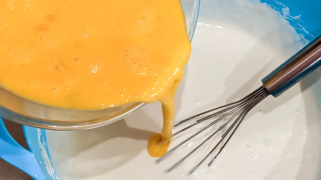 pouring eggs into cheesecake mixture