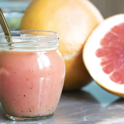 grapefruit vinaigrette salad dressing in a jar with a gold spoon and a grapefruit in the background
