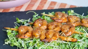 miso glazed shrimp skewers on a black slate with greens