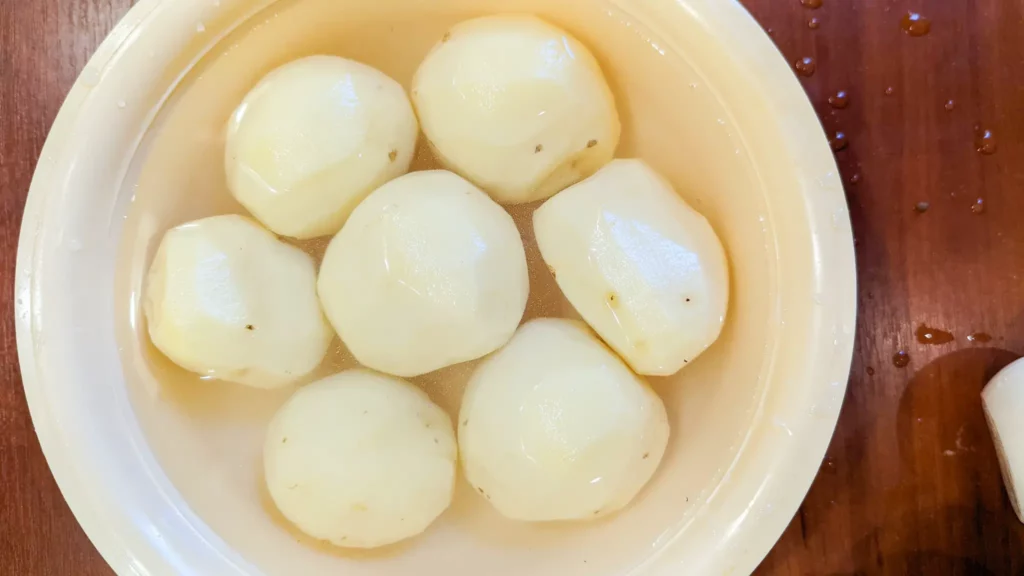peeled and washed potatoes sitting in a bowl of water on a table