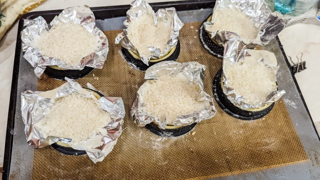 tartelette shells filled with foil and rice to pre-bake