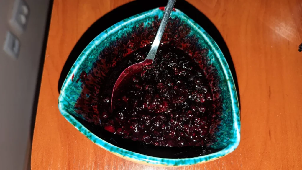 bowl of blackcurrant compote with metal spoon