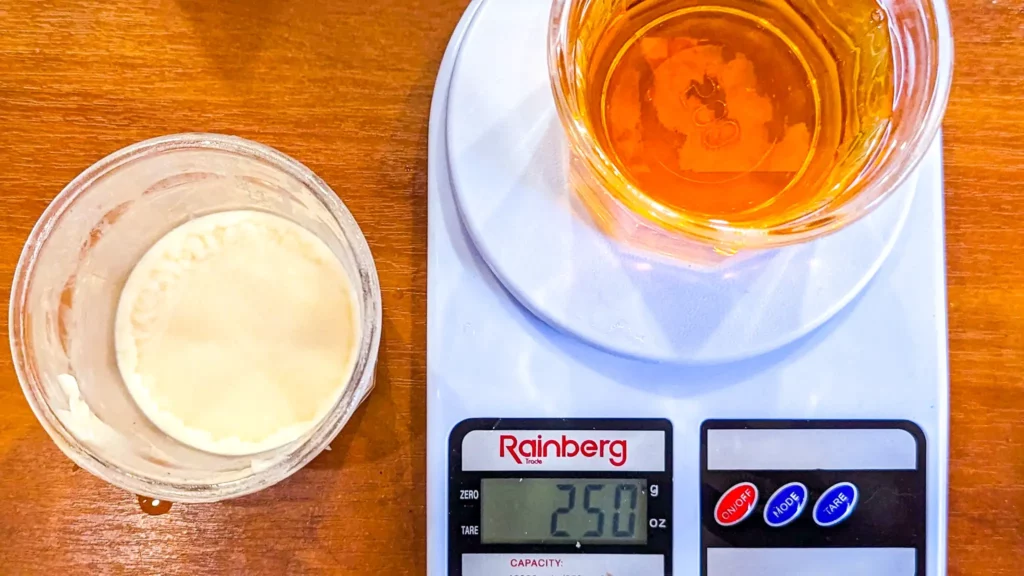 a jar of duck fat next to a kitchen scale with 250g of bourbon in it