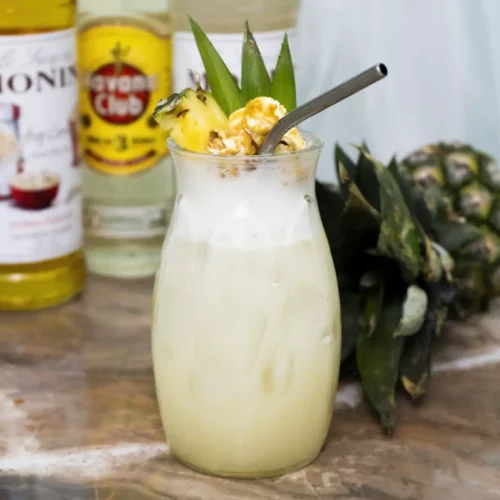 popcorn colada cocktail with pineapple and other ingredients in the background