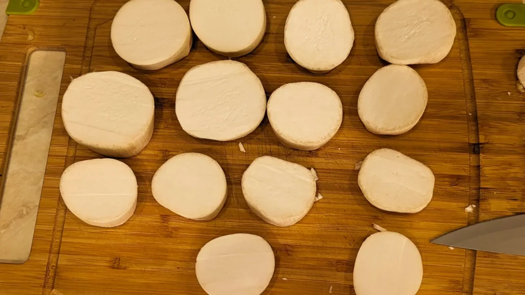 a cutting board with sliced eryngi mushrooms for a chinese recipe