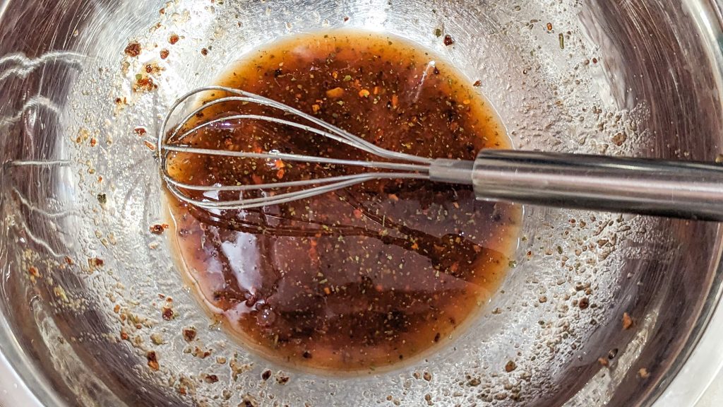 chili lime wing sauce in a metal bowl with a wire whisk